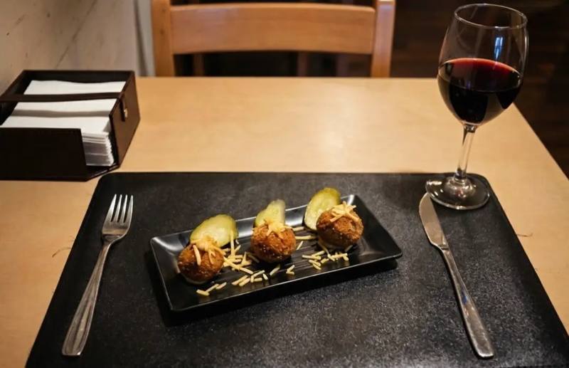 Entrada en plato negro con cubiertos y una copa de vino tinto