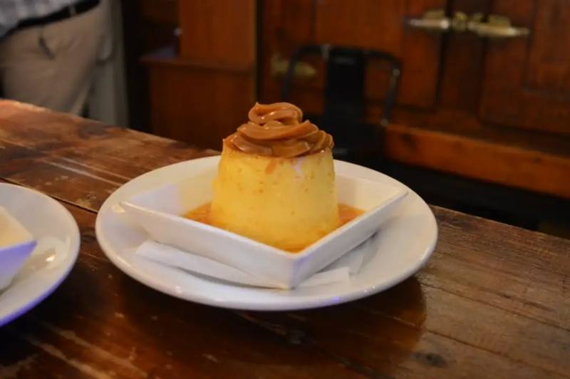 Flan casero con dulce de leche sobre una mesa de madera