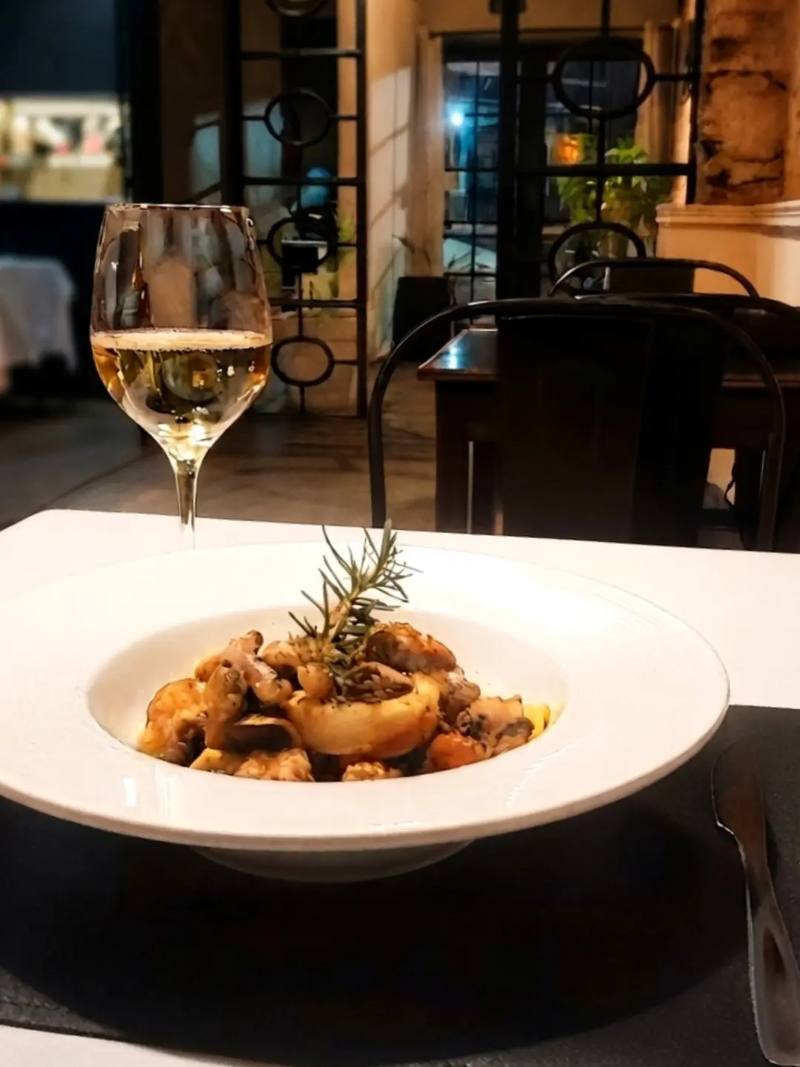 Pasta con frutos de mar y copa de vino blanco en una mesa del salón