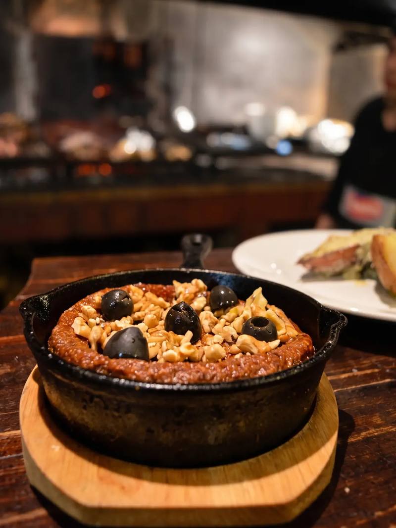 Provoleta gratinada en sartén de hierro con nueces y aceitunas negras