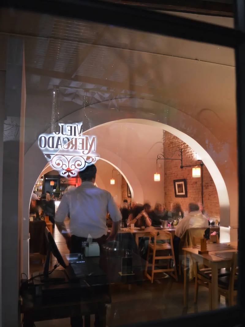 El cartel de Viejo Mercado en la ventana y, detrás, el salón con arcos